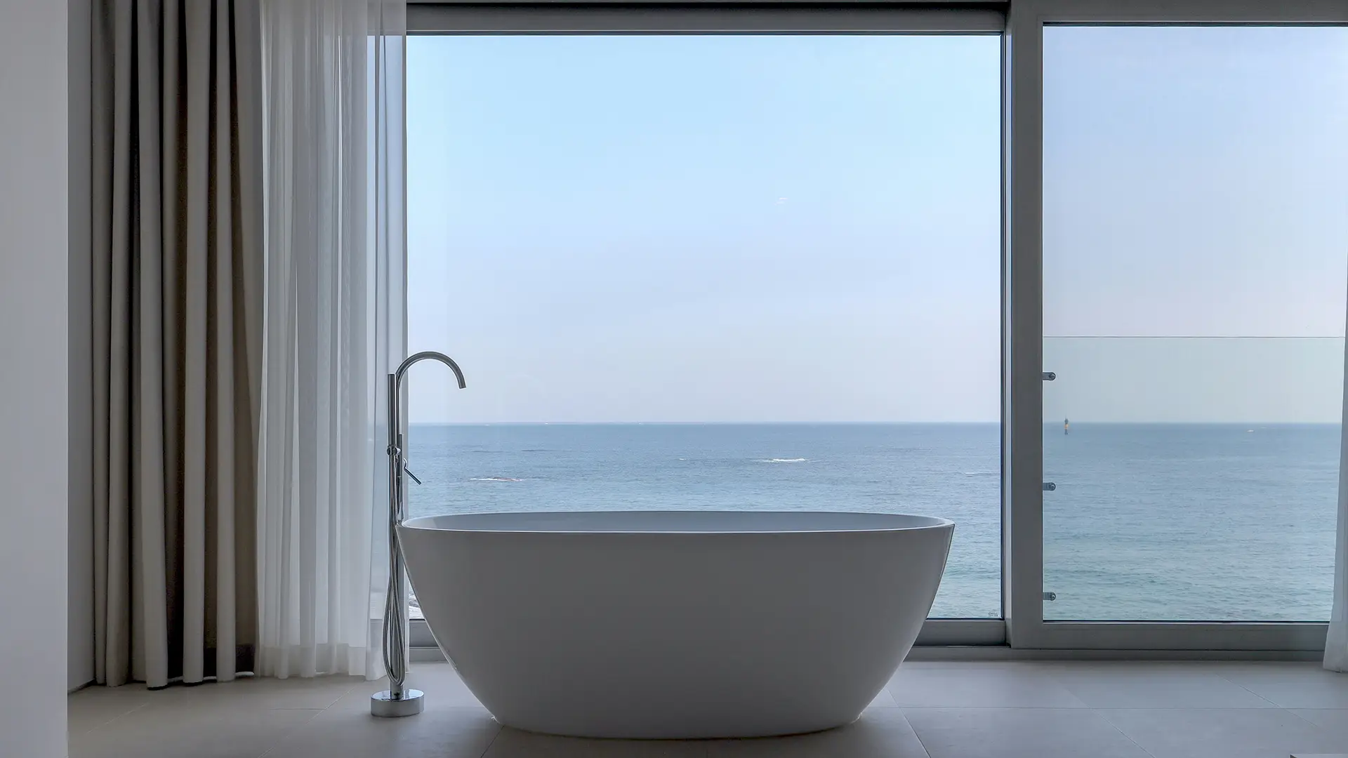 Bathroom window with clear smart glass offering a view of the ocean.